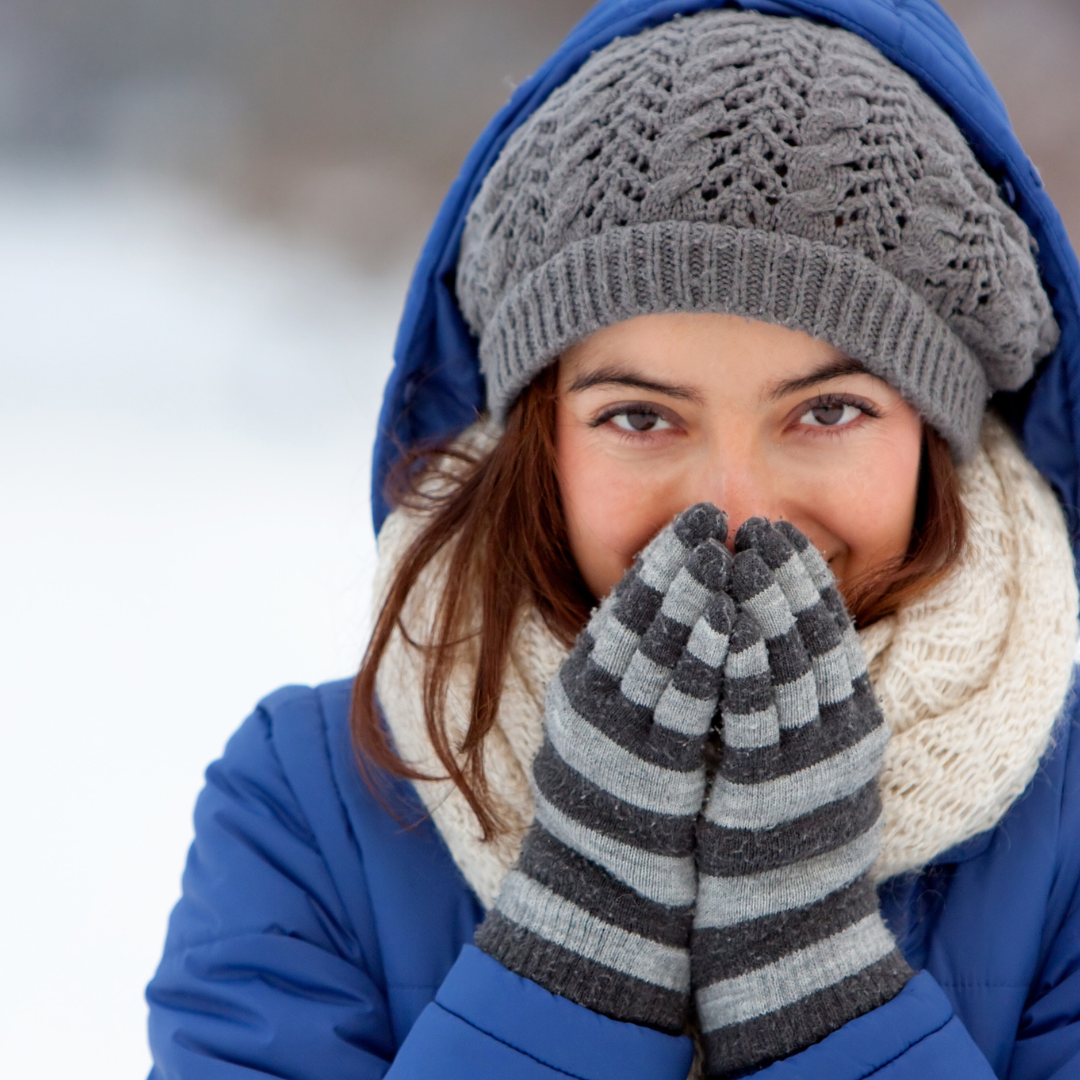 Woman covering mouth with gloves dressed in winter clothes outside