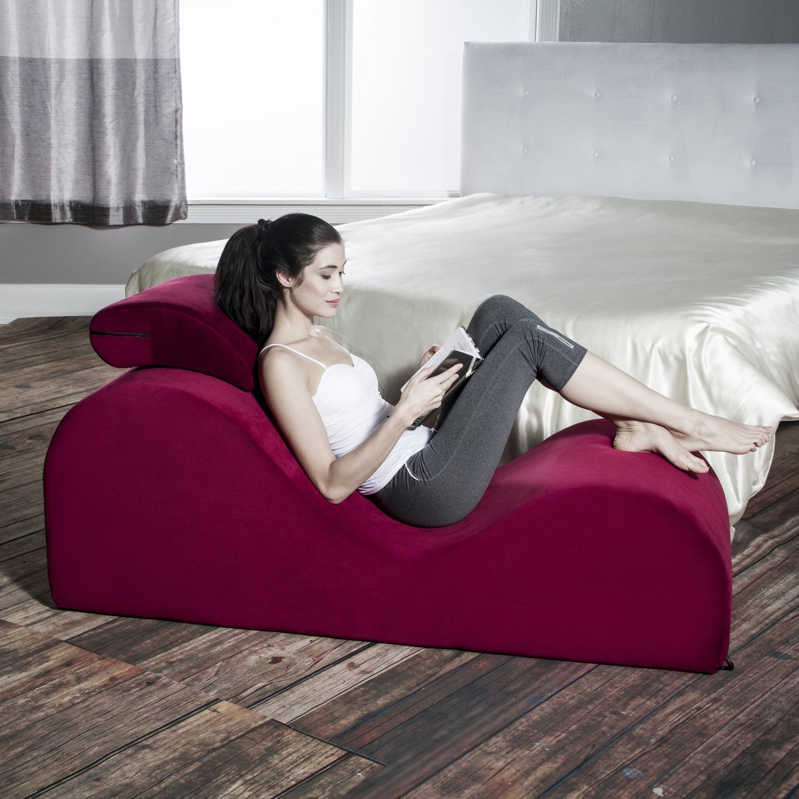 woman sitting on a long burgundy couch reading