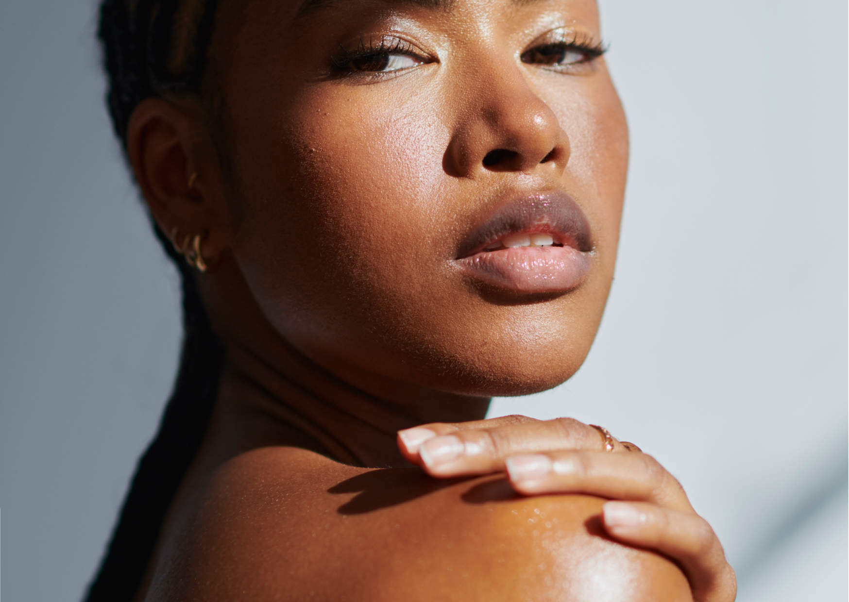 Person looking over their shoulder at the camera, as if applying body cream