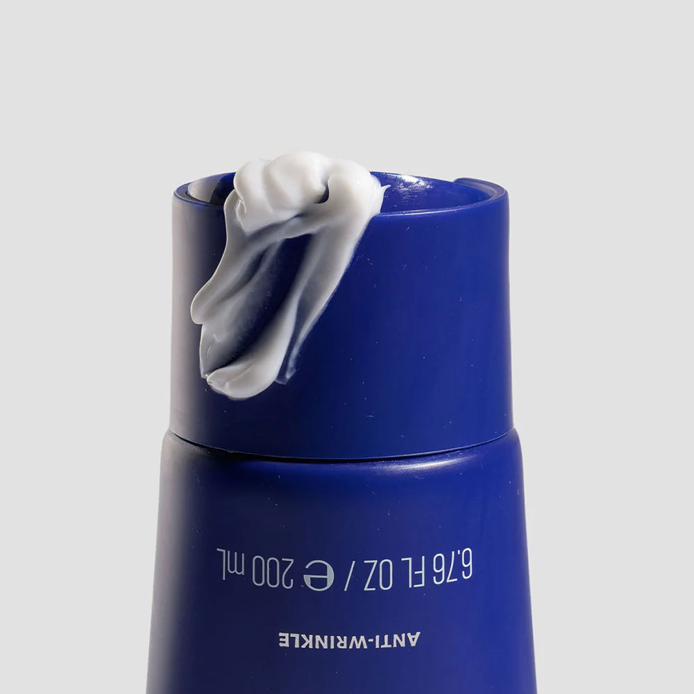 Blue skincare bottle with white cream on a gray background