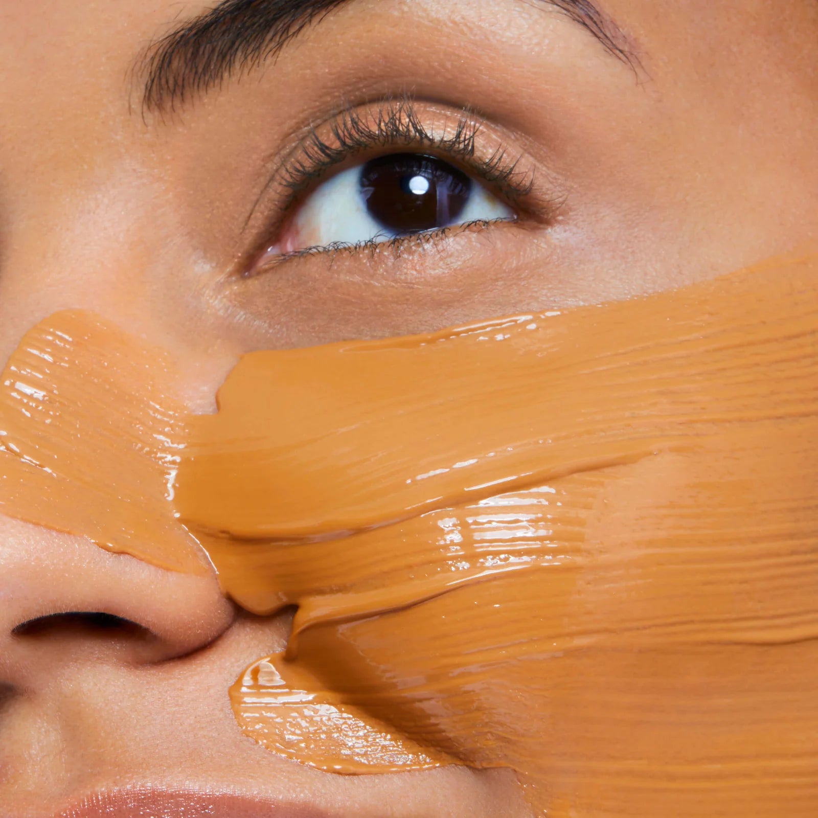 Close-up of a person's eye with orange mask applied to the face