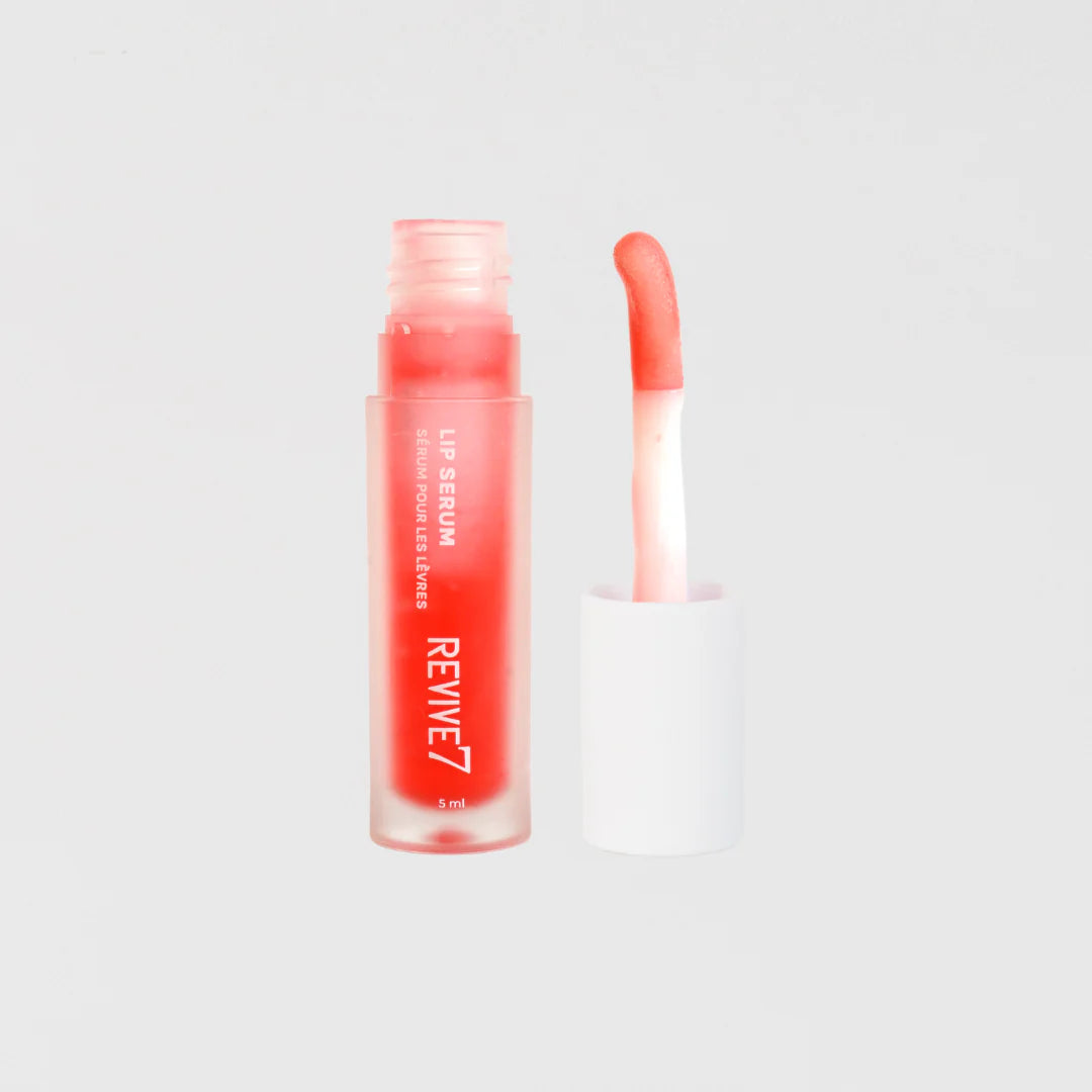 A tube of Revive7 Lip Serum with the cap removed, showing a clear liquid inside with a red applicator beside it.