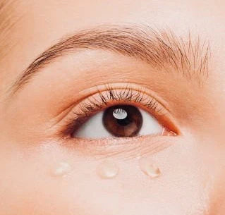 Close-up of a person's eye with visible droplets on skin