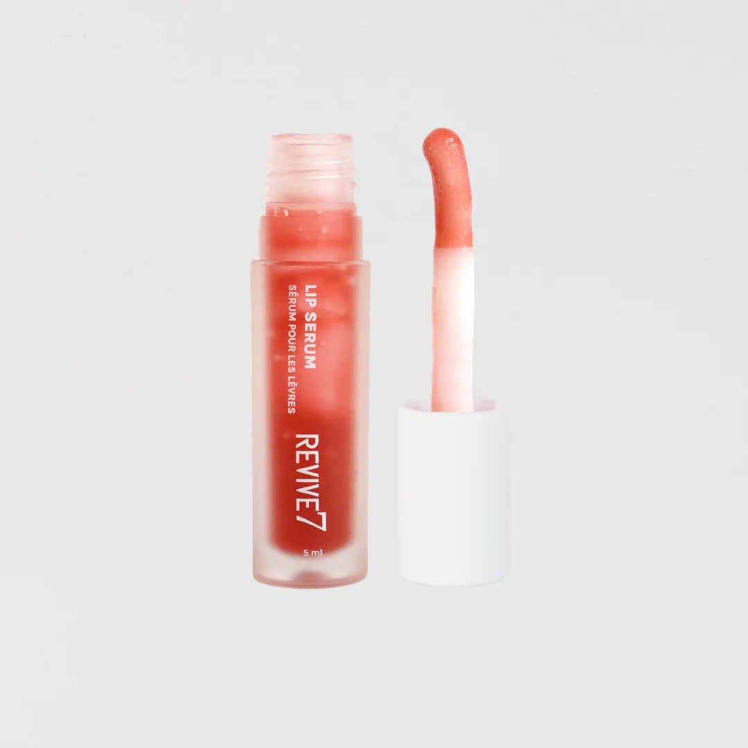A tube of Revive7 Lip Serum with the cap removed, showing a clear liquid inside with a pink applicator beside it.