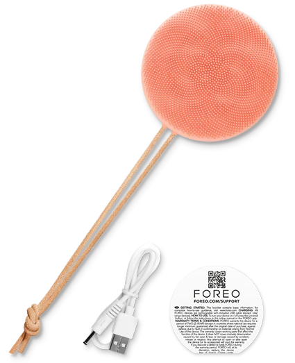 Coral-coloured FOREO body brush with wooden handle and USB cable on a white background