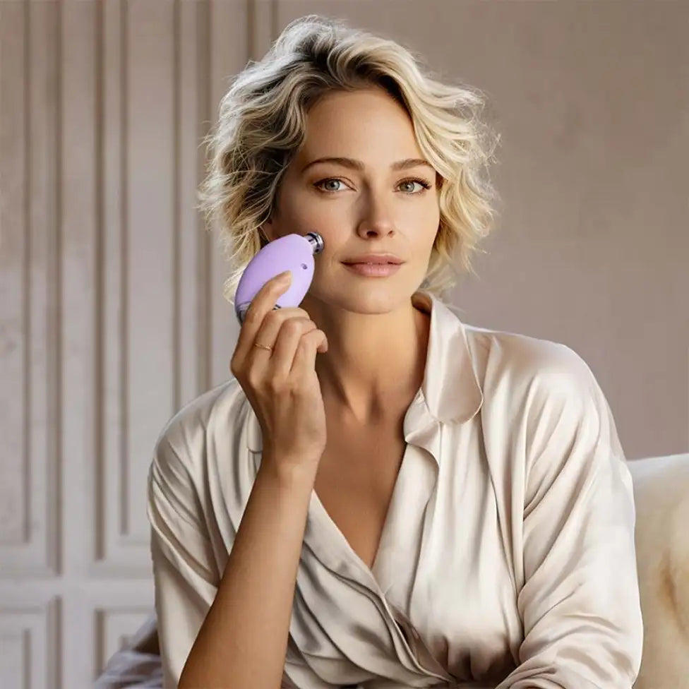 Woman holding purple device to her cheek