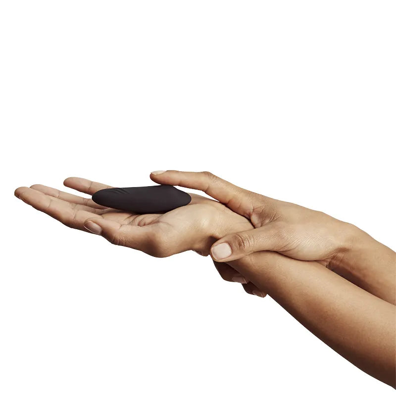 Hand holding a black stone against a white background