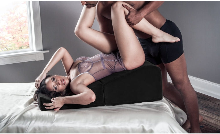 couple on a black positioning ramp on a bed