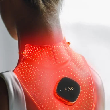 A person shown from the back wearing a glowing red neck and upper shoulder heating pad with a black control module. The product is illuminated to show heat coverage on the neck and upper back.