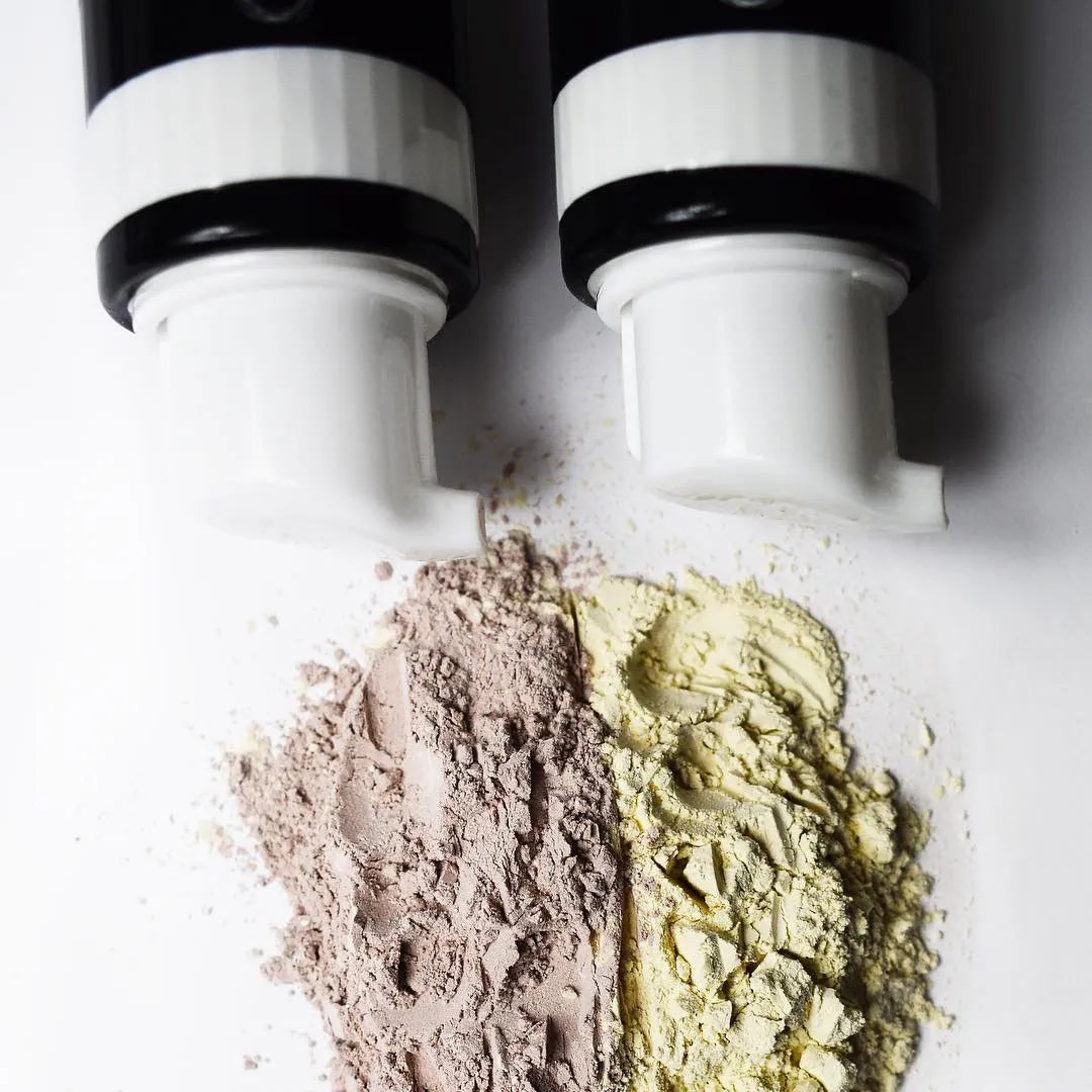 Two containers with beige and brown powders on a white background