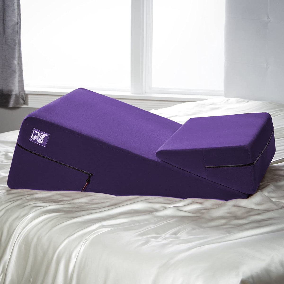 Purple wedge pillow on a bed with white bedding