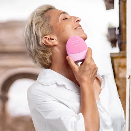Woman holding pink device to her face