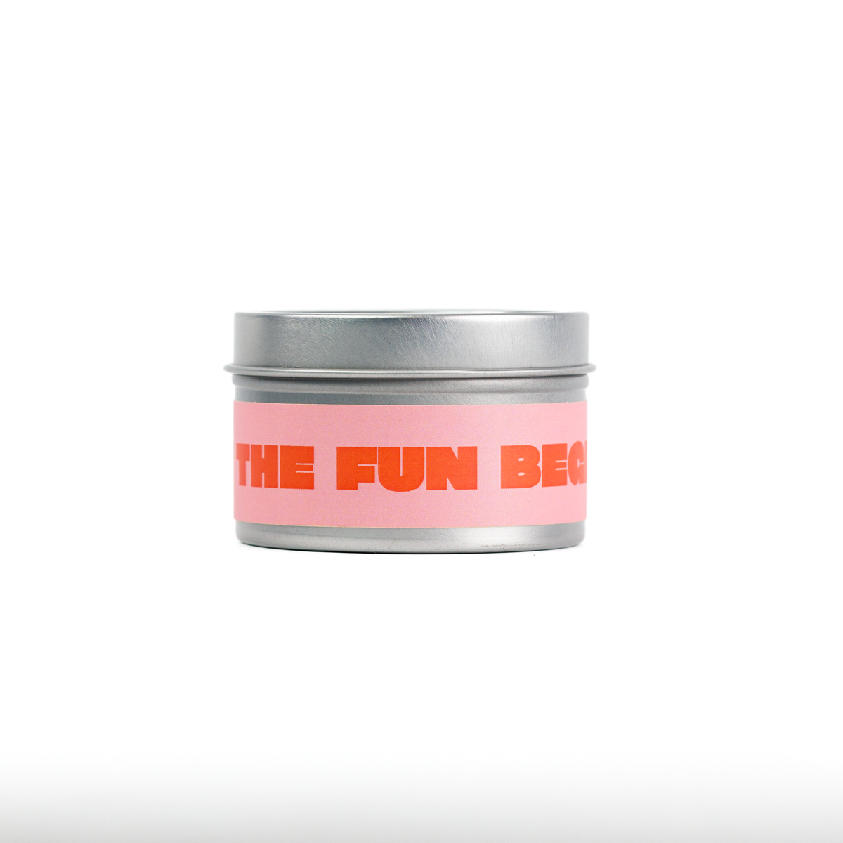 A small round metal tin with a silver lid and a pink label featuring orange text that reads 'THE FUN BE...'.
