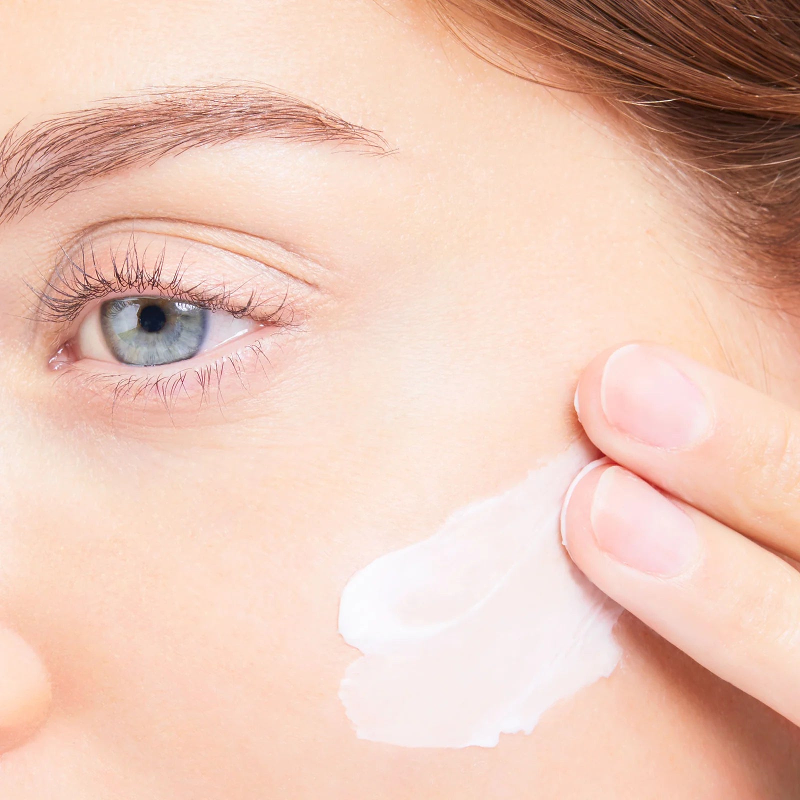 Close up of person putting moisturizer on her cheek