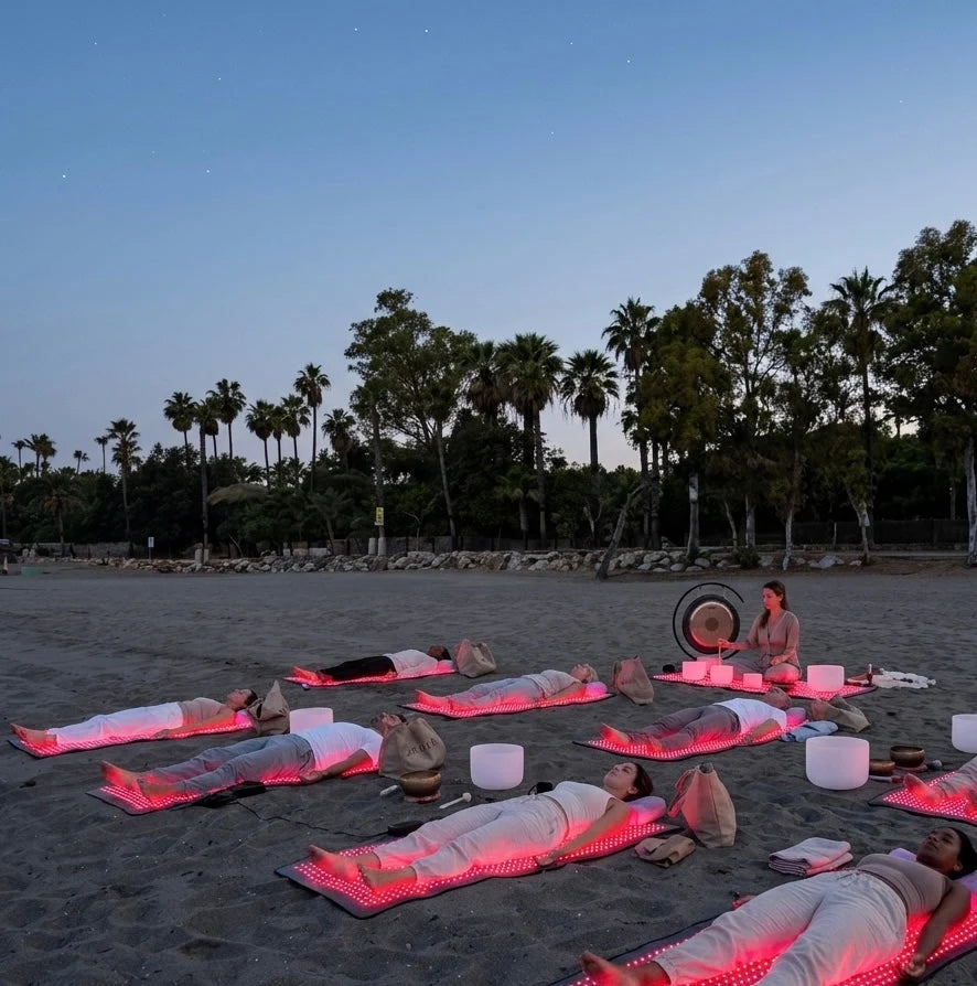 people lying on red light mats on a beach
