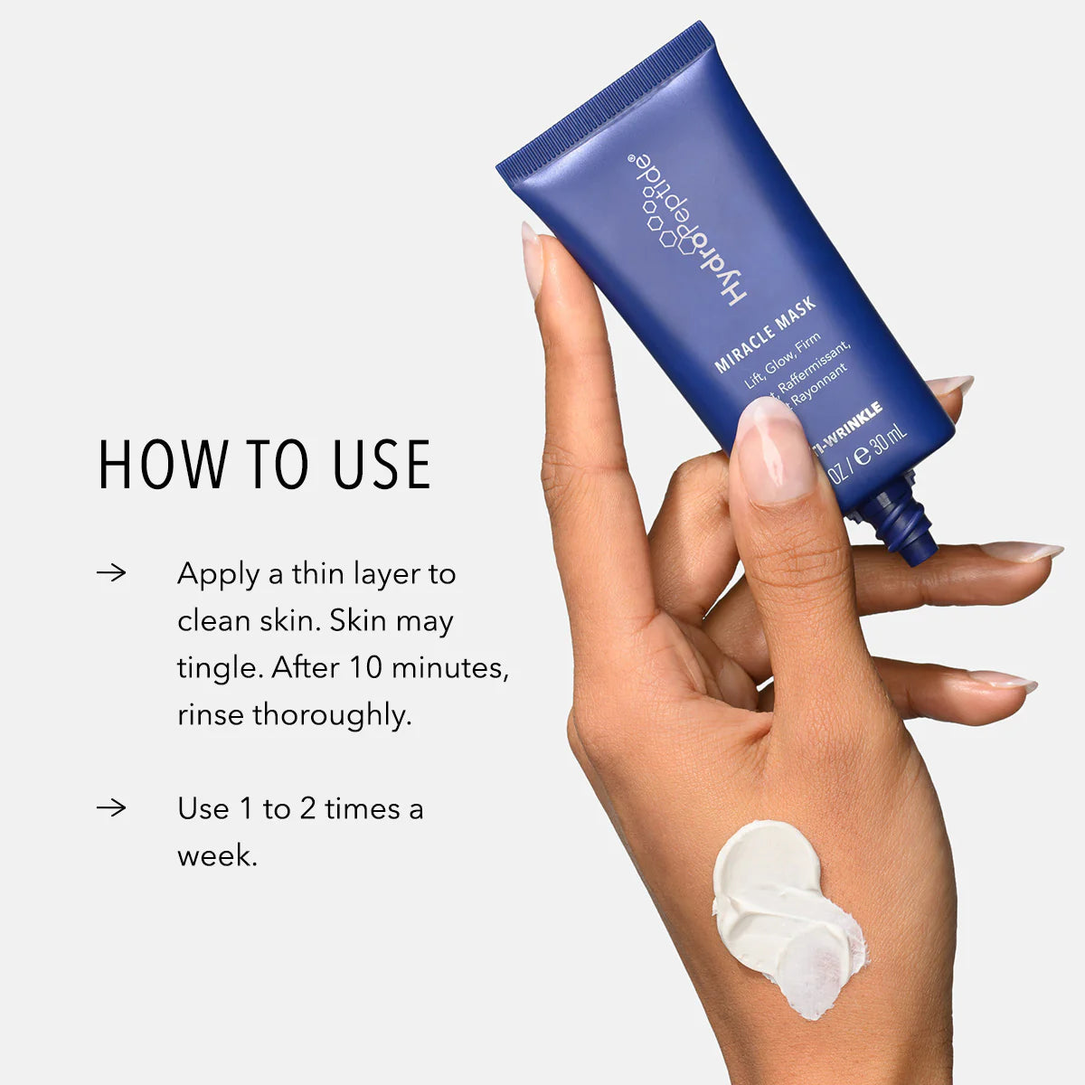 Hand holding a blue skincare product with application instructions on a white background