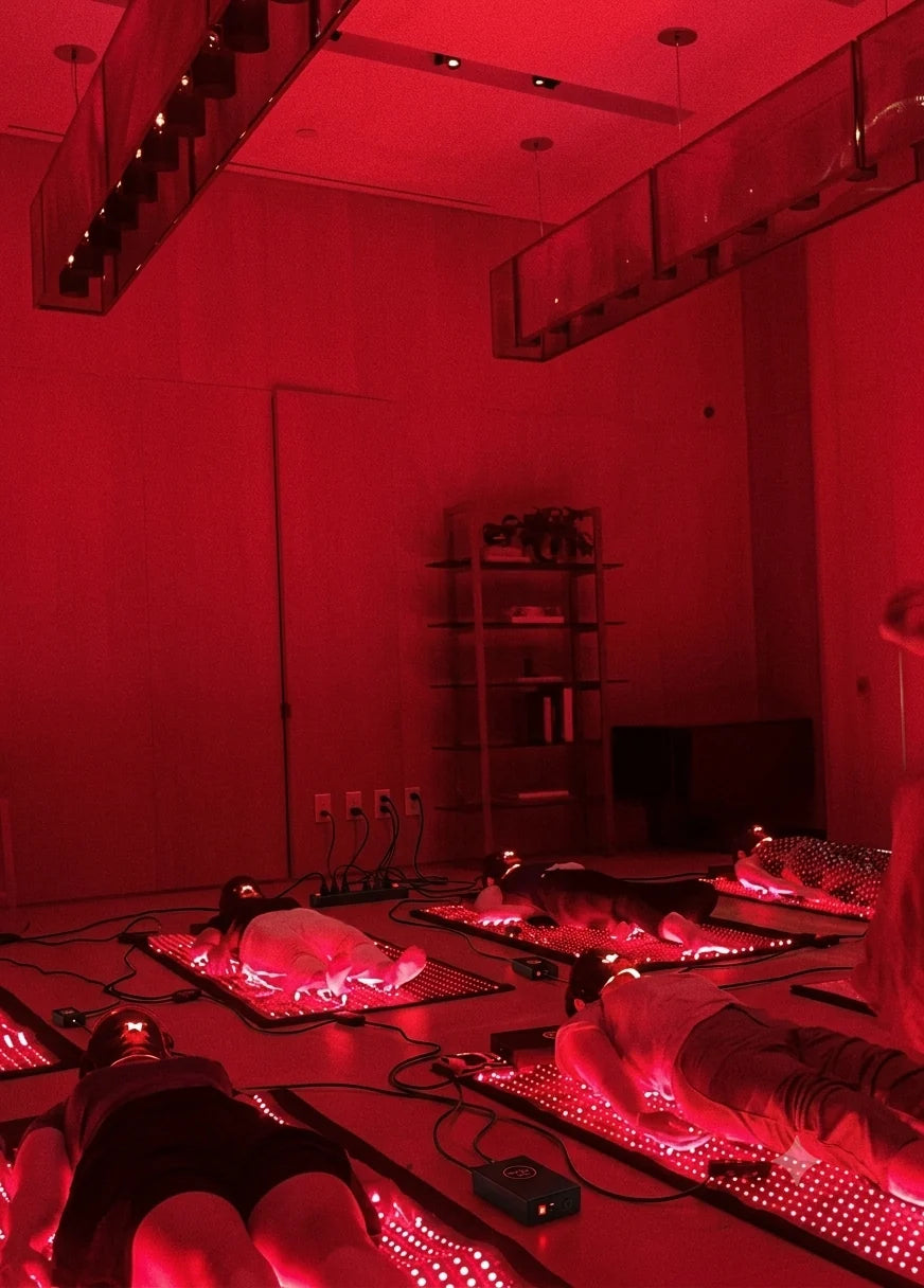 people lying on red light mats in a room