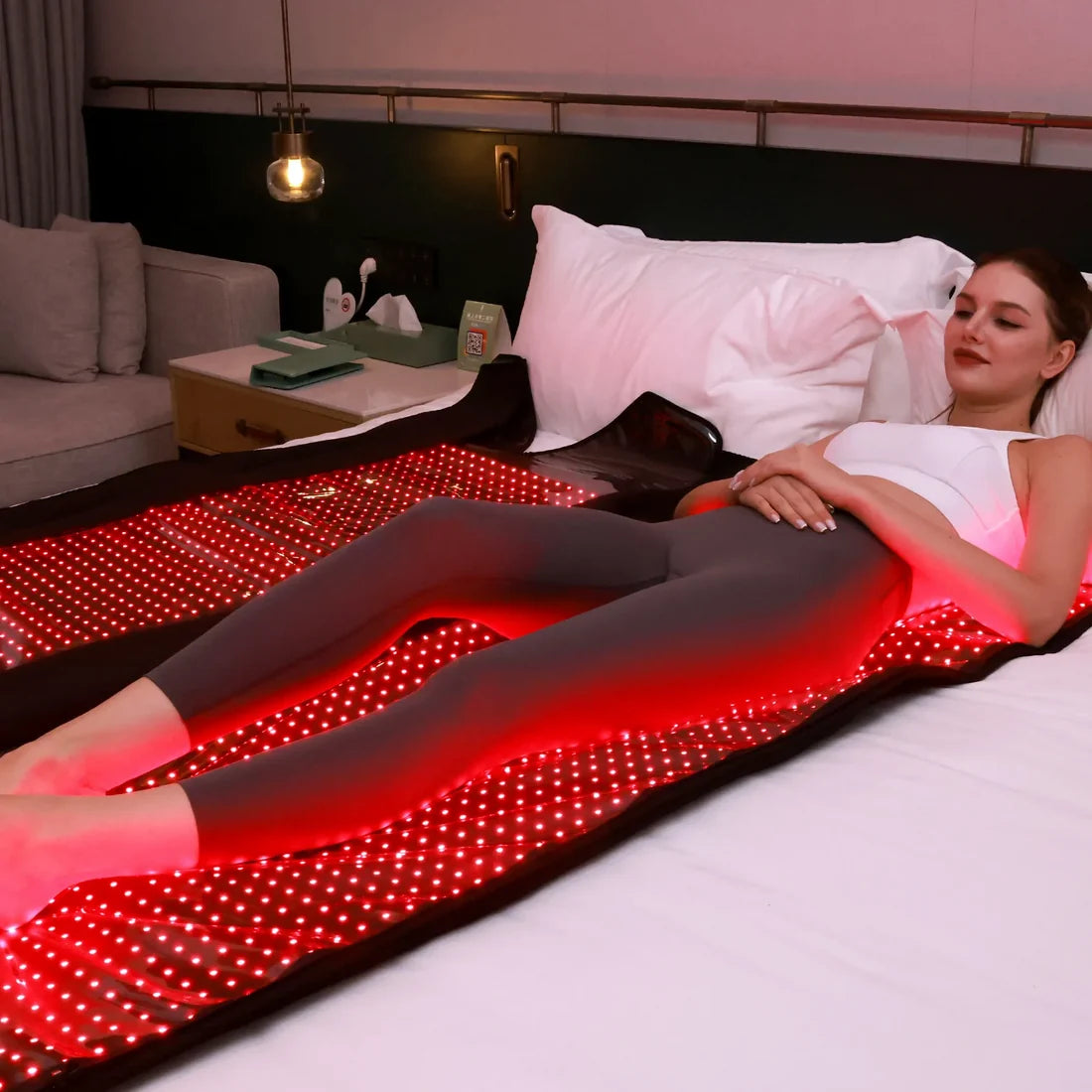 woman lying on red light therapy blanket on a bed