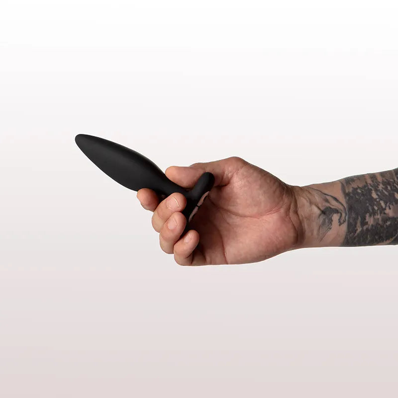 Hand holding a black object against a white background
