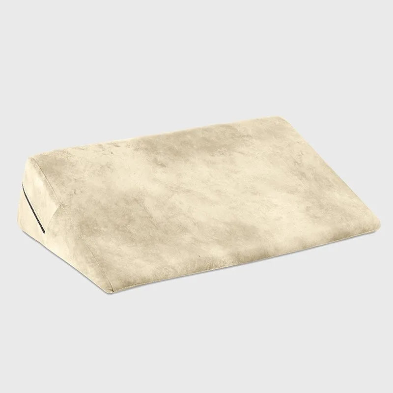 A wedge-shaped memory foam pillow in a light beige color, shown at an angle on a neutral light gray background.