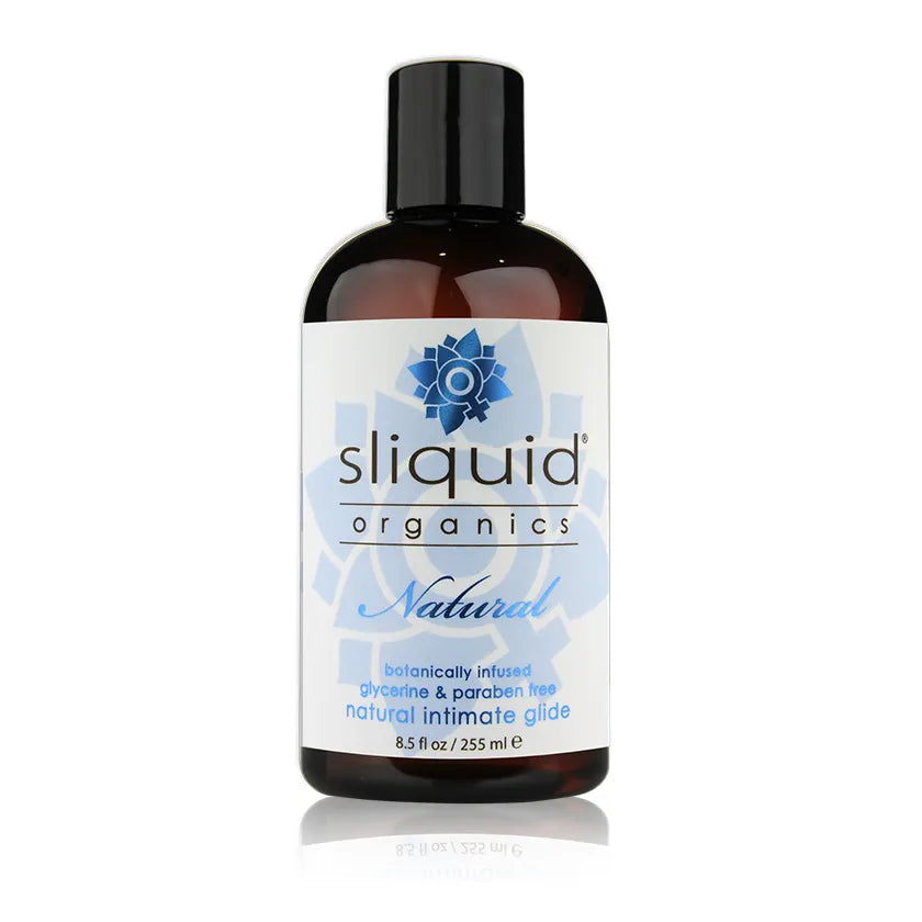 A bottle of Sliquid Organics Natural Intimate Glide on a clean white background with a subtle reflection. The bottle is dark amber brown with a black cap and a white label featuring blue accents and the brand logo.