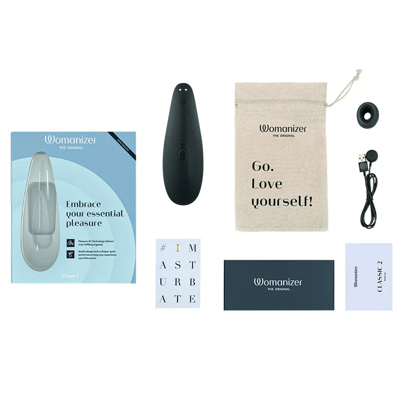 Womanizer product set including black device, packaging, and motivational pouch on a white background