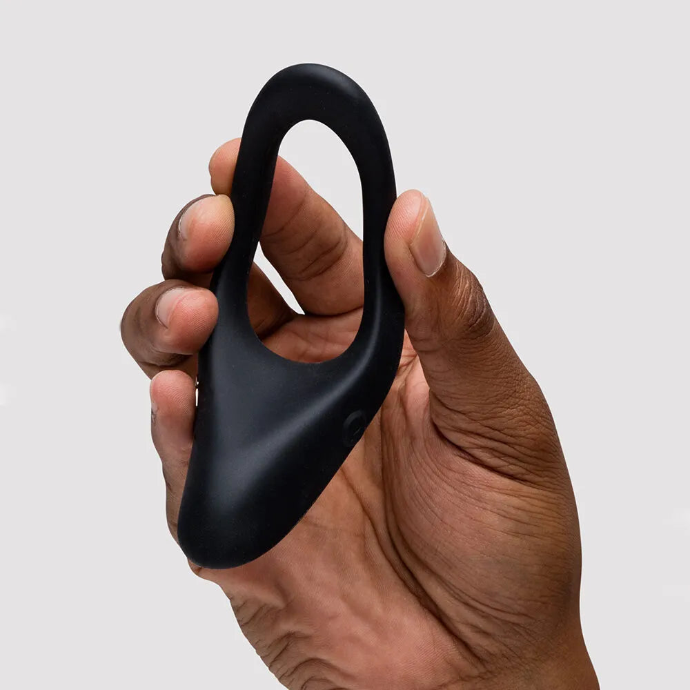 Hand holding a black silicone ring on a light gray background