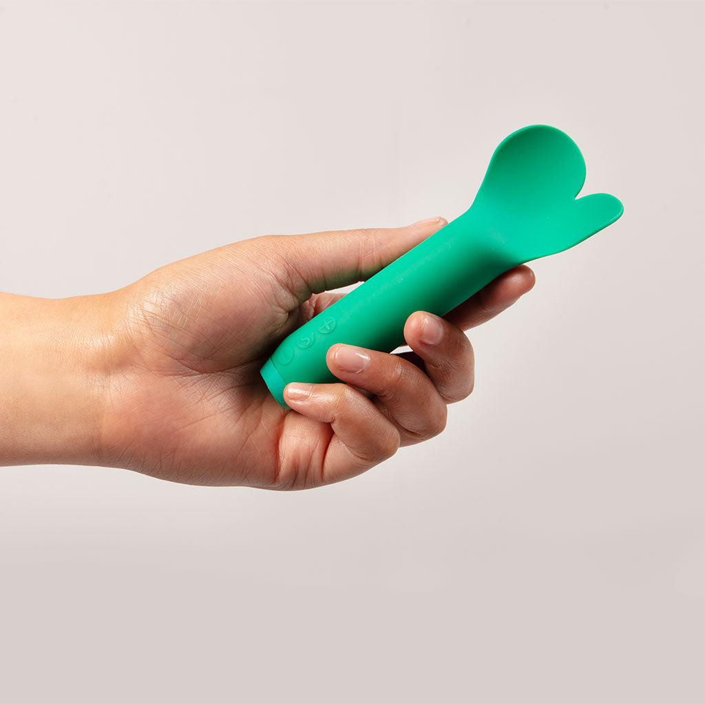Hand holding a green plastic tool against a plain background