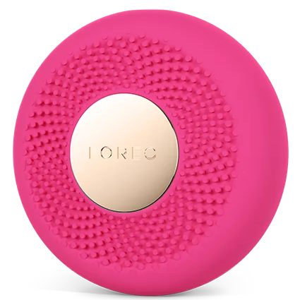 A circular pink facial cleansing brush with a textured silicone exterior and a central metallic gold button displaying the brand name 'IORIC'.