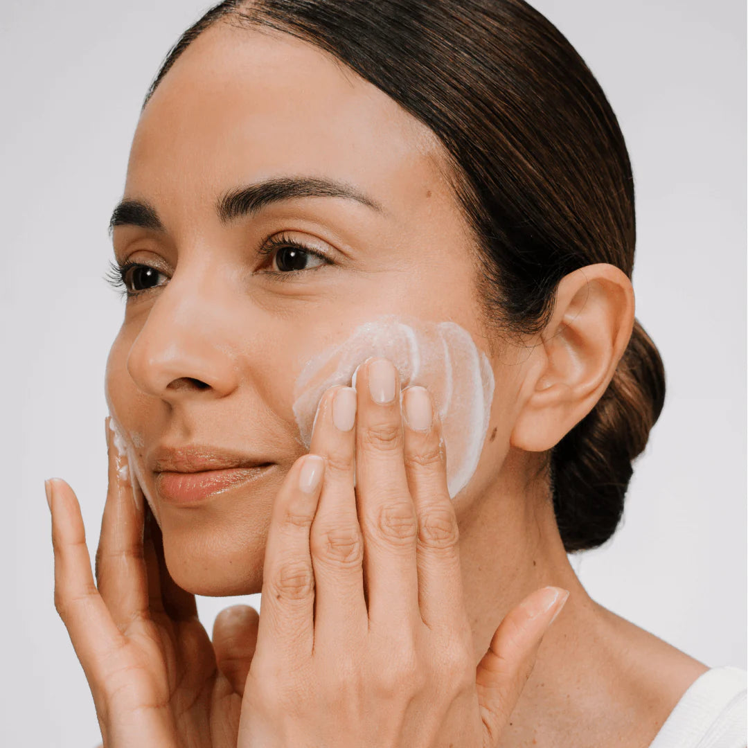 Person with cream on her cheeks, rubbing them