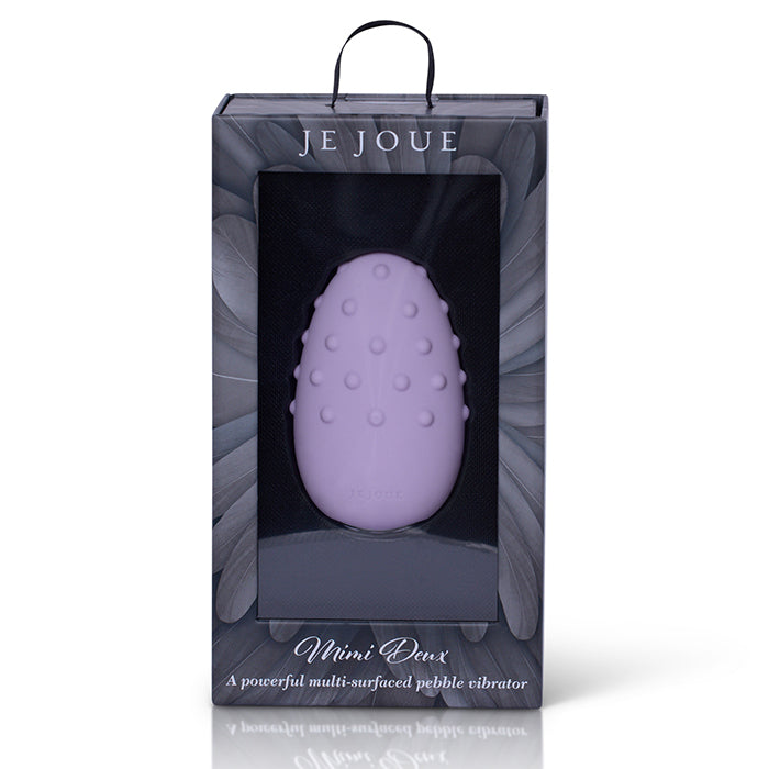Purple pebble-shaped vibrator in packaging with 'JE JOUE' branding on a white background