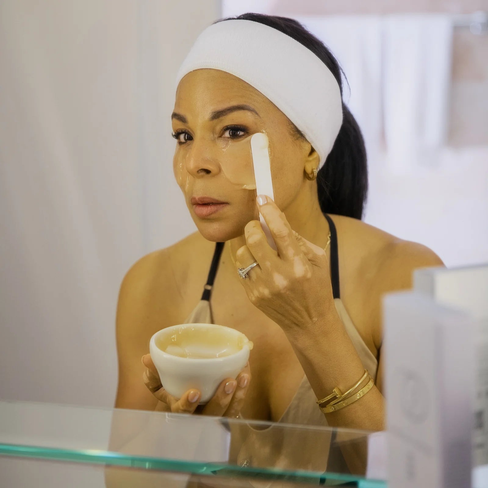Person applying CO2 Lift Pro Carboxy Therapy Topical Gel Mask to her face with an applicator while holding a bowl 