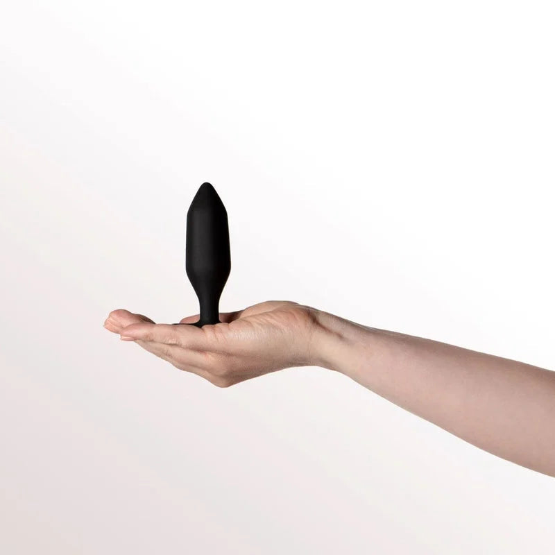 A black silicone personal massager held in the open palm of a person's hand against a clean white background.