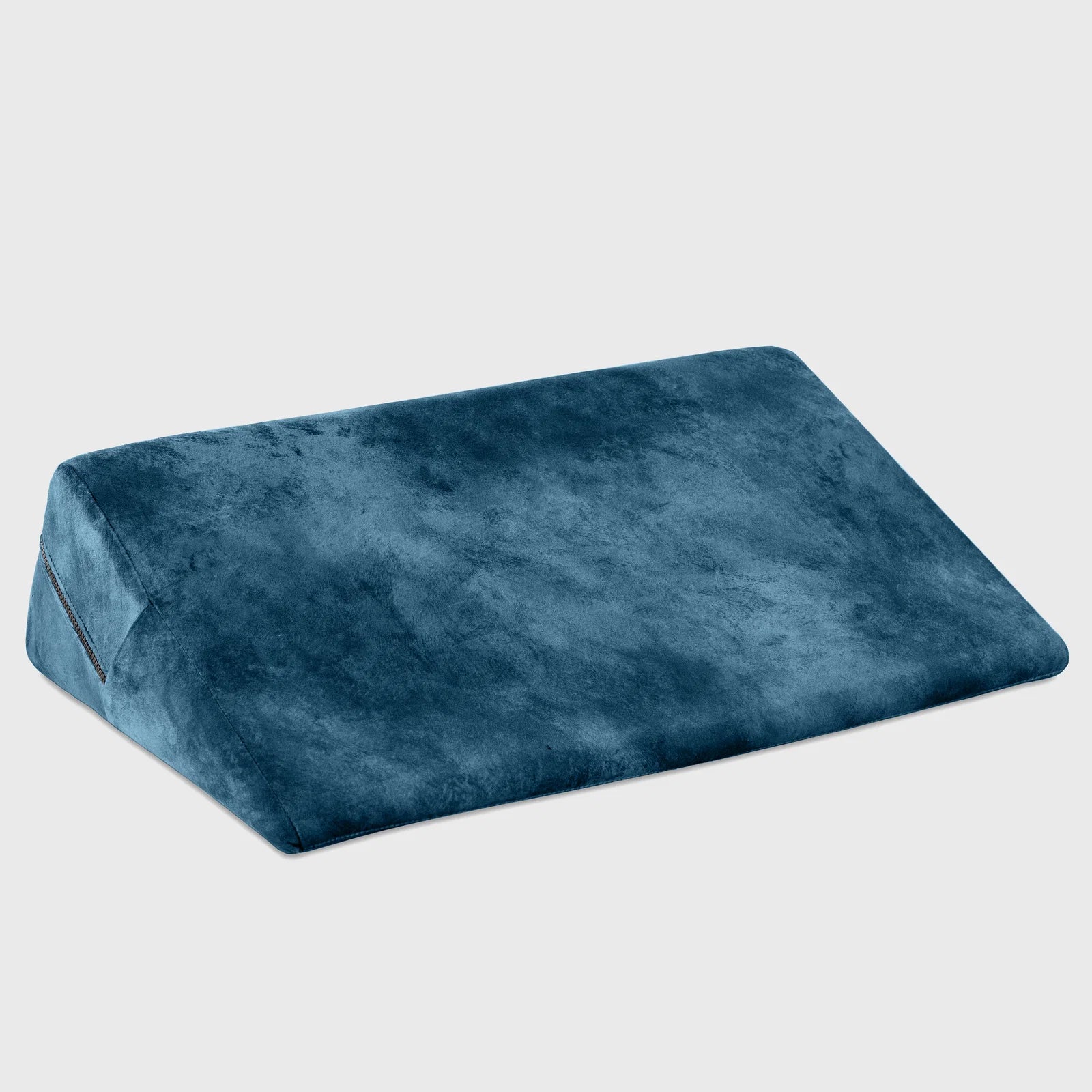 A wedge-shaped lumbar support pillow in a textured navy blue fabric, shown at an angle on a light gray background.